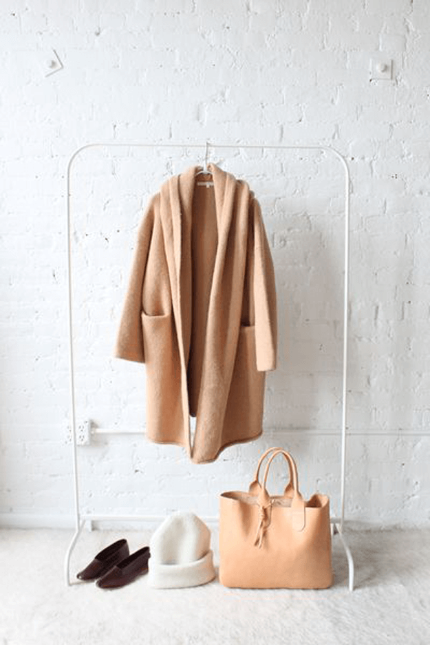 camel brown coat against white brick wall