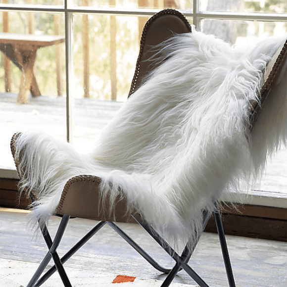 ivory white sheepskin rug draped over leather sling chair