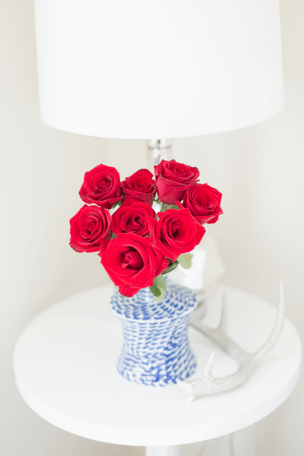 red roses in blue vase on white table