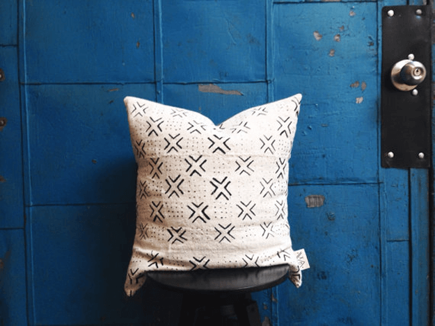 white african mudcloth tribal pillow against blue door