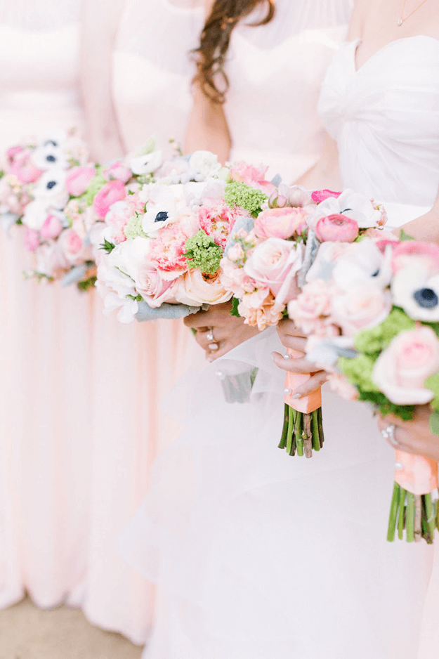 bridesmaids in pale pink dresses with colorful bouquets