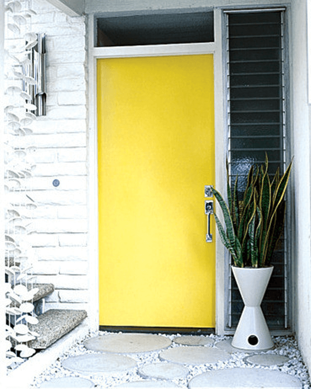 bright yellow front door in white painted brick wall