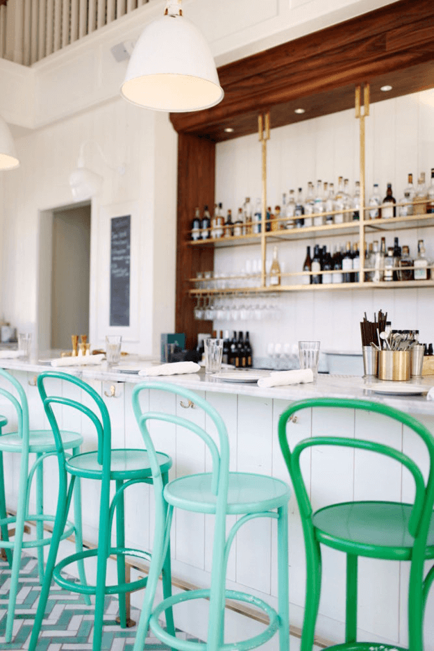 white bar interior with jade green cafe stools